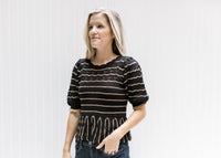 Model wearing a short sleeve black sweater with rust stripes and a babydoll fit. 