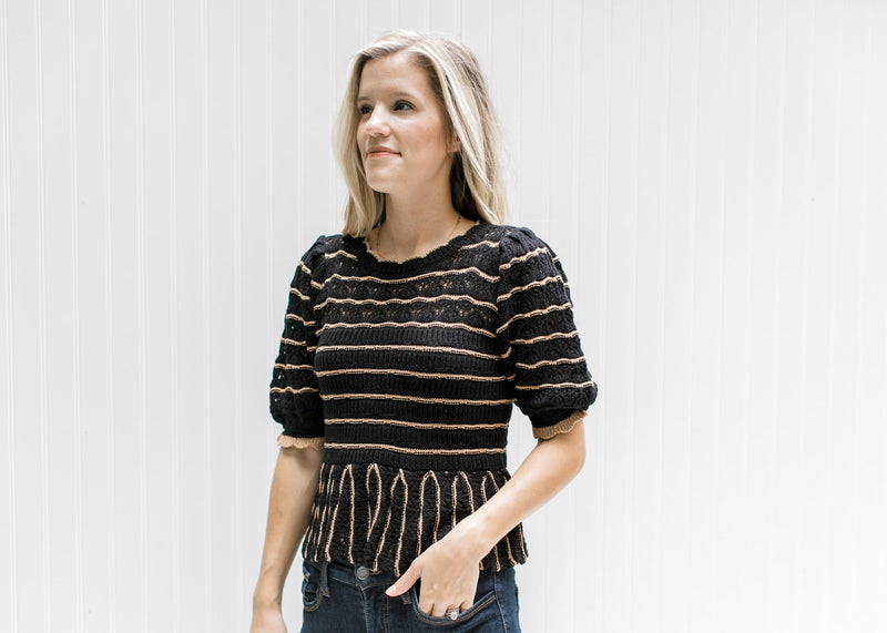 Model wearing a short sleeve black sweater with rust stripes and a babydoll fit. 
