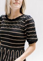 Model wearing a short sleeve black sweater with rust stripes, scalloped detail and a babydoll fit.