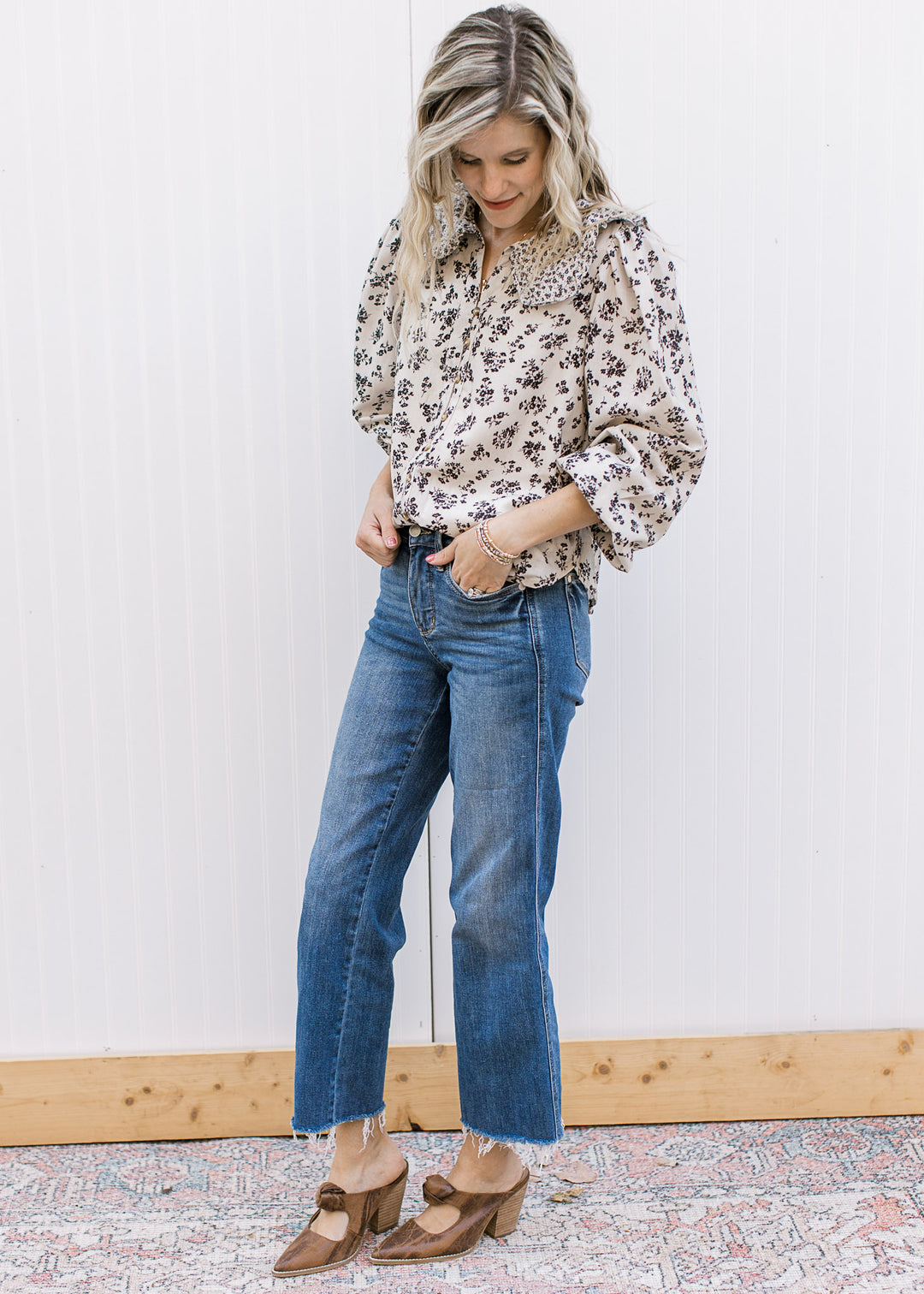 Model wearing jeans, heals and a tan button up top with black microfloral and bubble long sleevs.