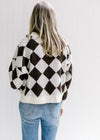 Back view of Model wearing a brown and white diamond pattern sweater with long sleeves.
