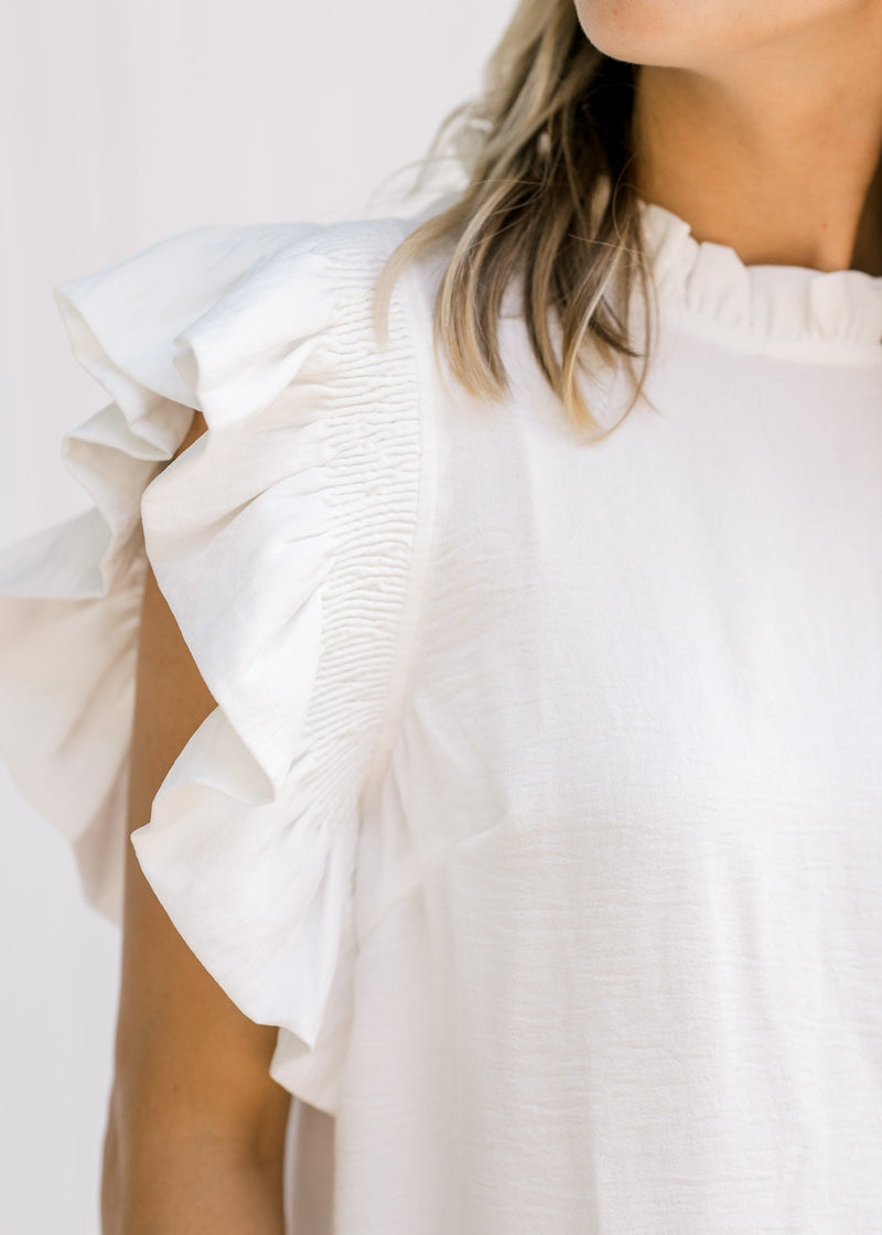 Close up view of white flutter capped sleeve on a black and white colorblock top. 