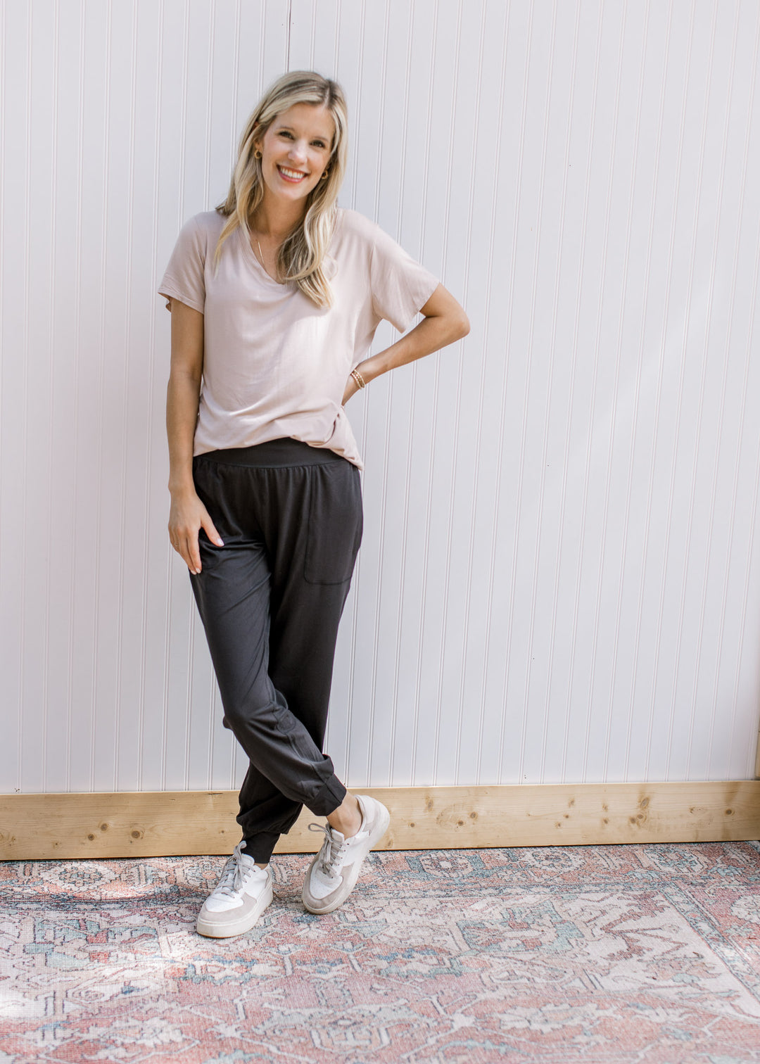 Model wearing a tan top with black athleisure joggers with elastic waist and stretchy material.