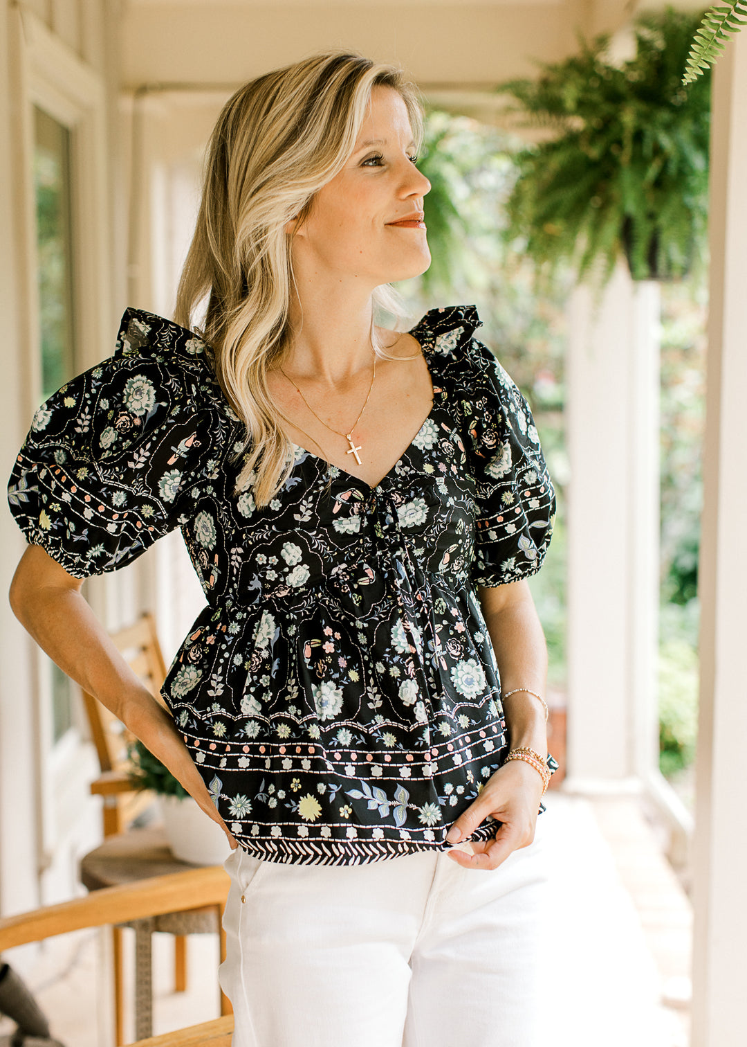 Model wearing a black peplum top with bright floral, bubble short sleeves and a sweetheart neck. 