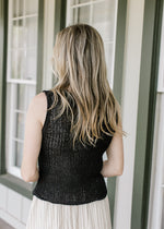 Back view of Model wearing a midi and a black knit vest with two button closure and a v-neck. 