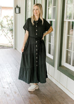 Model wearing mules with a lightweight black washed denim maxi with button front and belt tie.