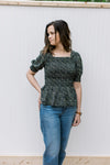 Model wearing a black peplum top with ditsy floral, smocked bodice and bubble short sleeves.