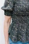 Close up of smocked bodice and cuff on a black peplum top with ditsy flowers.