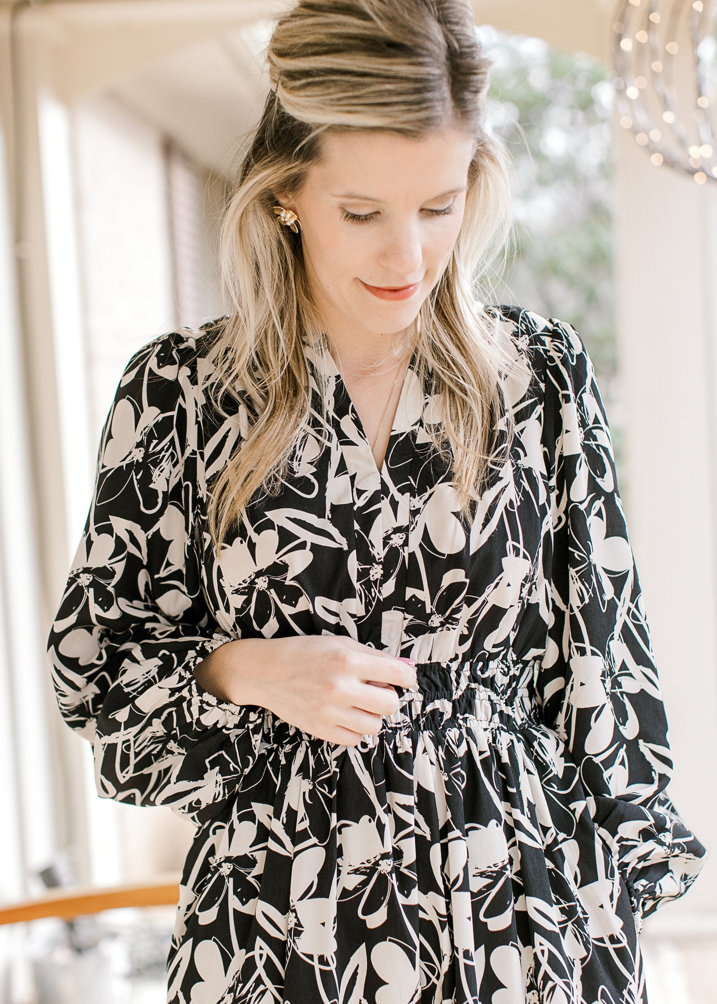 Close up of v-neck and smocked waist on a black midi with white flowers and long bubble sleeves.