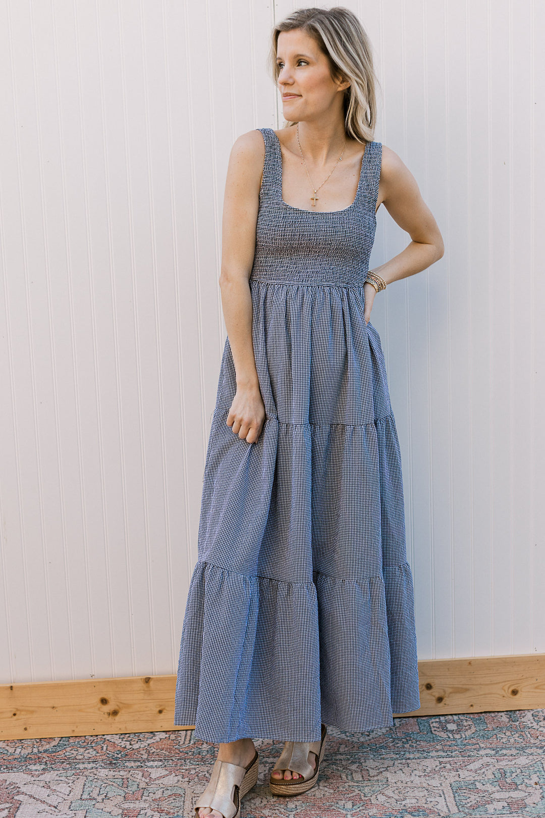 Model wearing a sleeveless black and white gingham midi with smocked bodice and straps. 