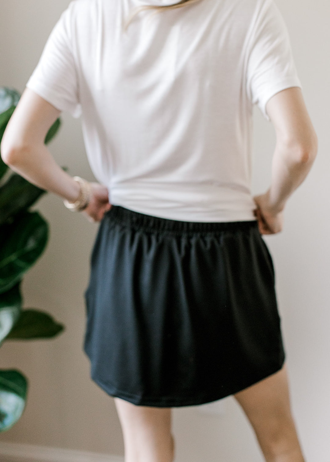 Back view of Model wearing a white top with short sleeves and a lightweight, stretchy fabric.