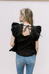 Back view of tie on the back of a black top with ruffle cap sleeves and a square neck. 