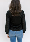 Back view of Model wearing a black top with a round neck and lace bubble long sleeves. 