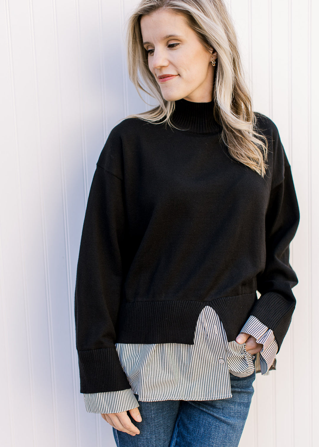 Model wearing a black sweater with attached black-and-white striped shirt with mock neck.