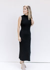 Model wearing booties with a black sleeveless dress with a mock neck, ribbed material and split hem.