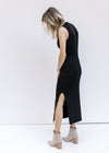 Side view of split hem on a model wearing a black sleeveless dress with a ribbed material. 