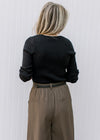 Back view of Model wearing a black v-neck sweater with long sleeves and a ribbed material. 