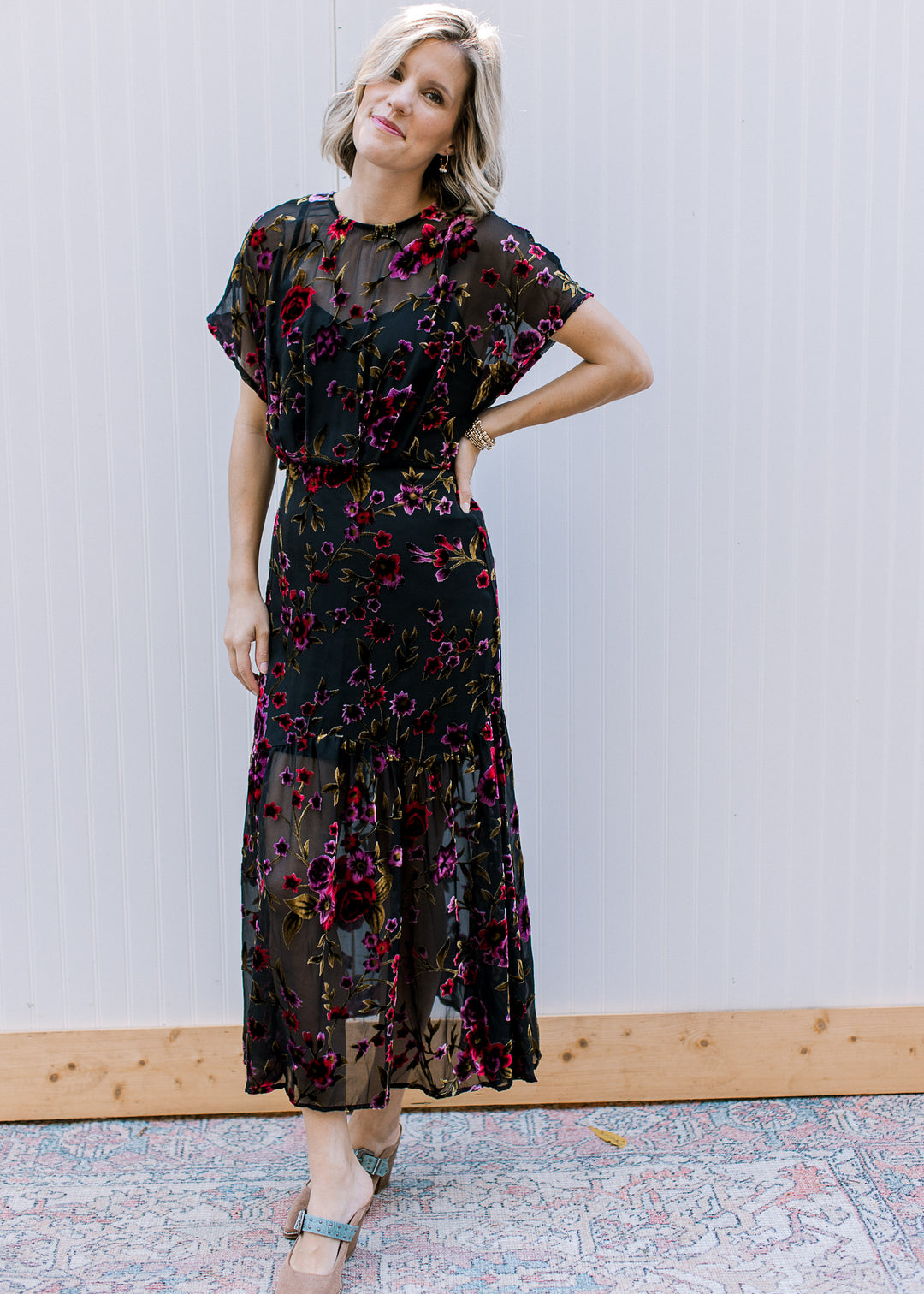 Model wearing a black midi with sheer overlay elastic waist, attached slip and short sleeves.