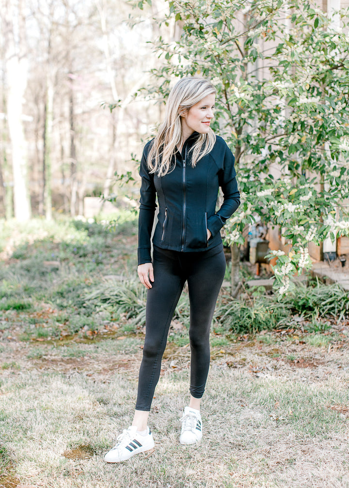 Model wearing sneakers, jacket and black leggings with full length and waistband pocket. 