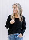 Model wearing a lightweight black ribbed top with long sleeves and a round neckline. 