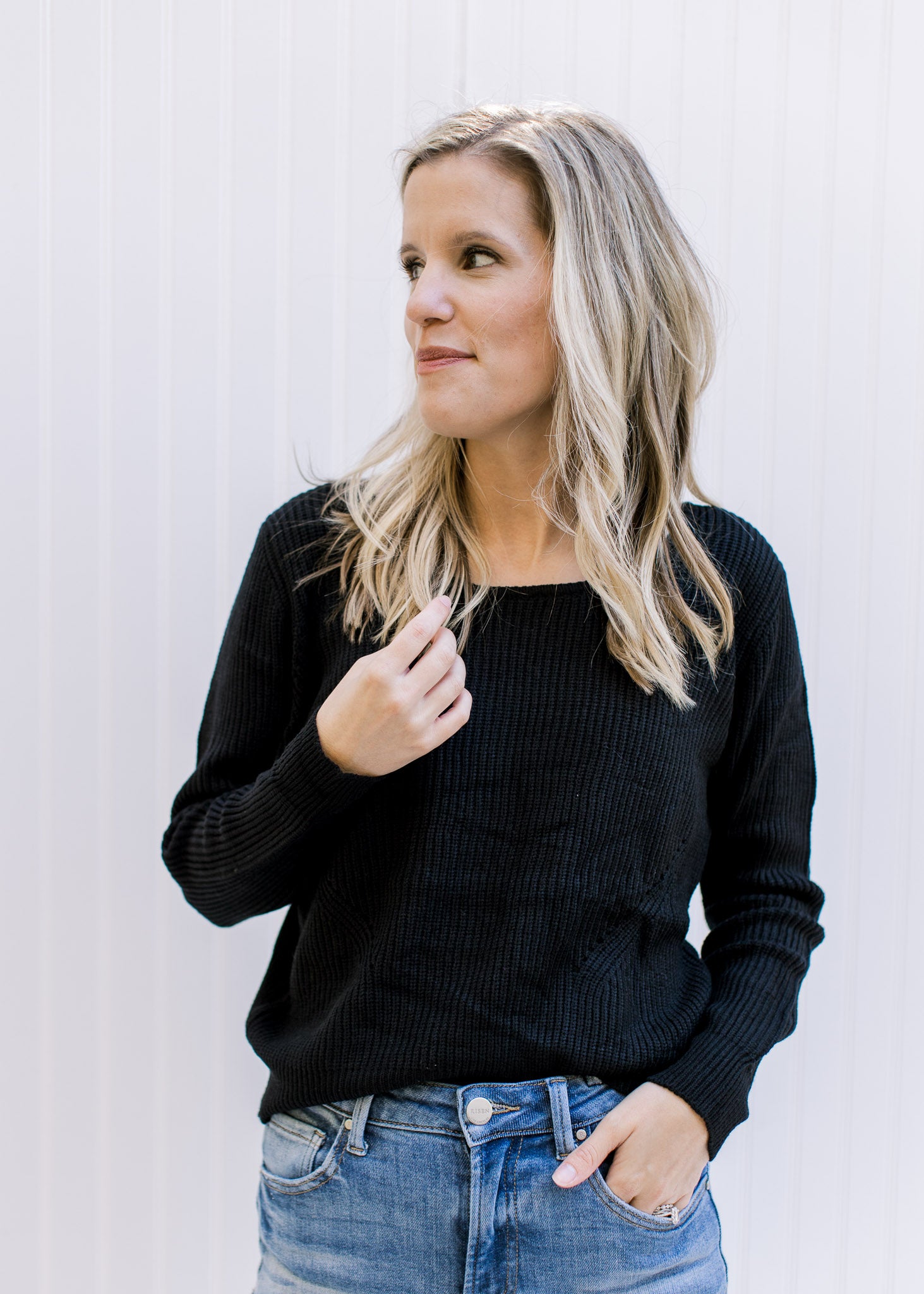 Model wearing a lightweight black ribbed top with long sleeves and a round neckline. 