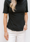 Model wearing a black ribbed top with short sleeved and ruffle neck and hem.