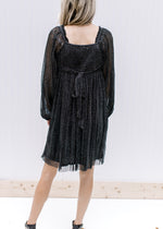 Back view of square neck and smocked back with a tie on a black shimmer above the knee dress. 