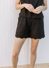Close up of lined black shorts with elastic waist and scalloped hem, comes with matching top. 