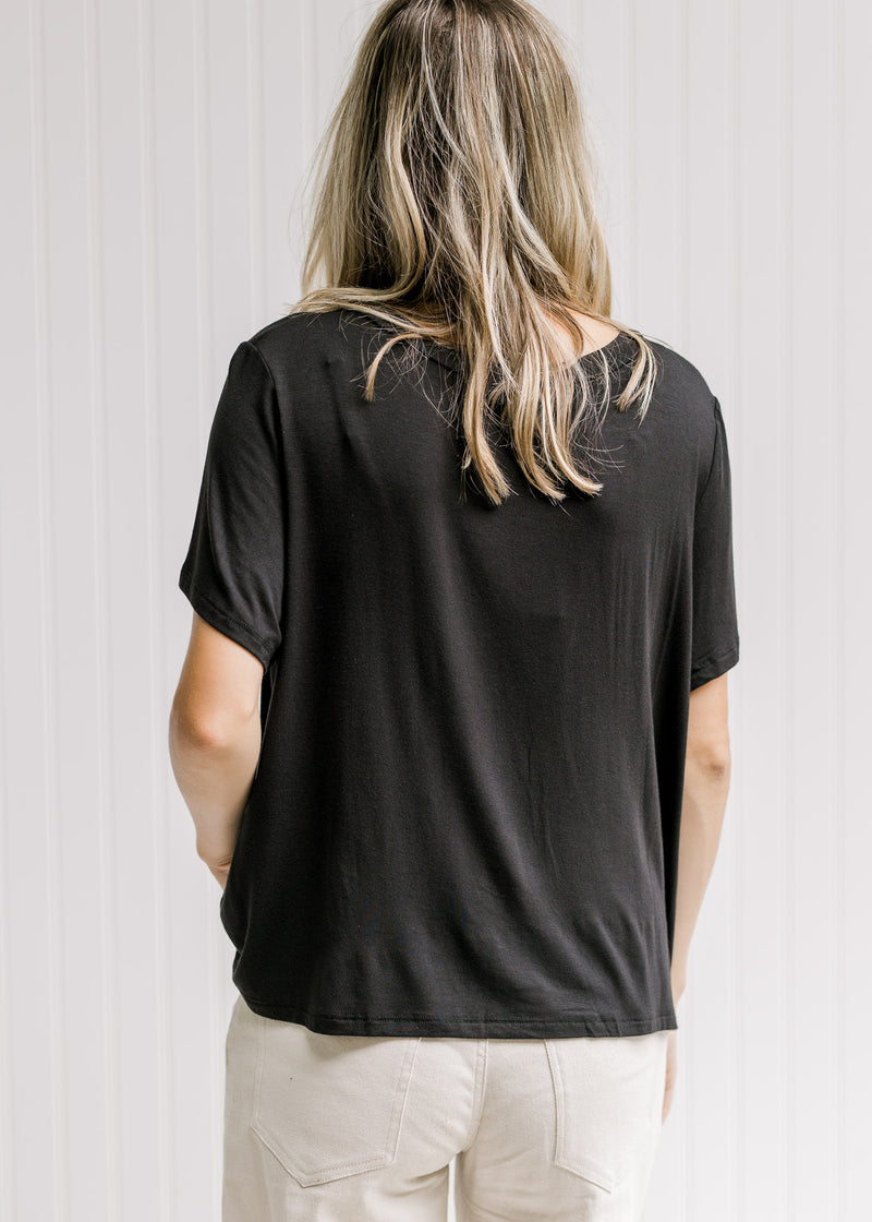 Back view of Model wearing a black short sleeve top with a slightly cropped fit. 