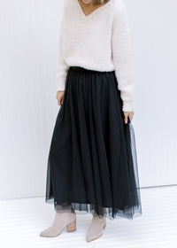 Model wearing booties with a black tulle maxi skirt with an elastic waist with a sheer overlay.