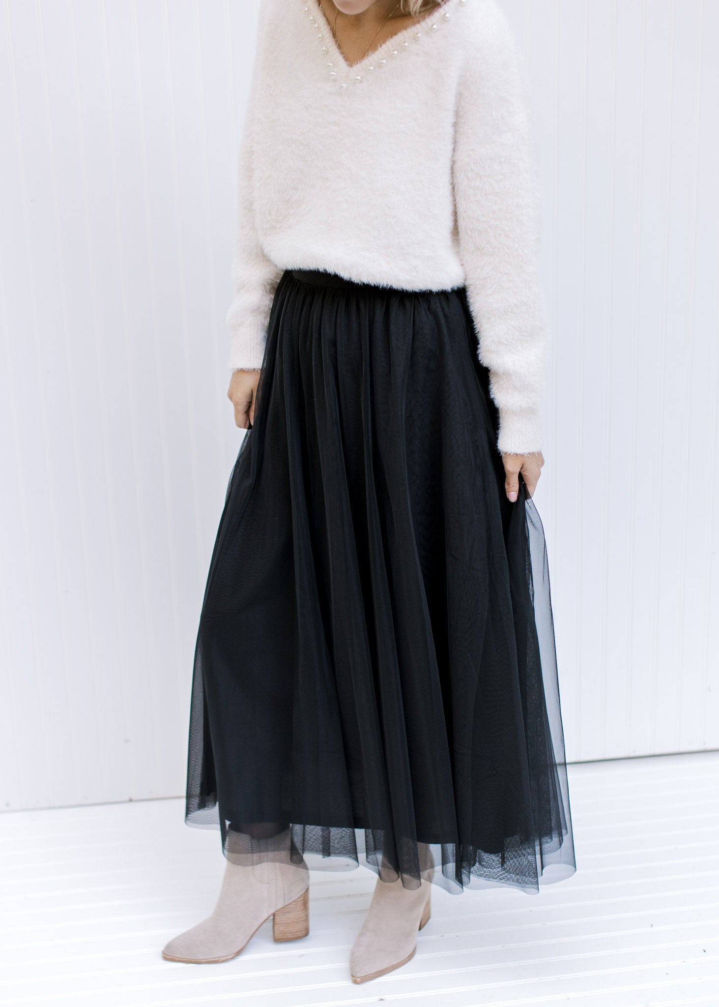Model wearing booties with a black tulle maxi skirt with an elastic waist with a sheer overlay.