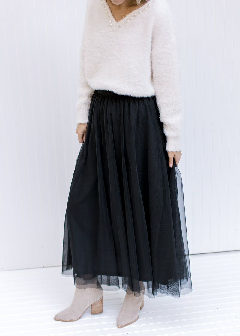 Model wearing booties with a black tulle maxi skirt with an elastic waist with a sheer overlay.