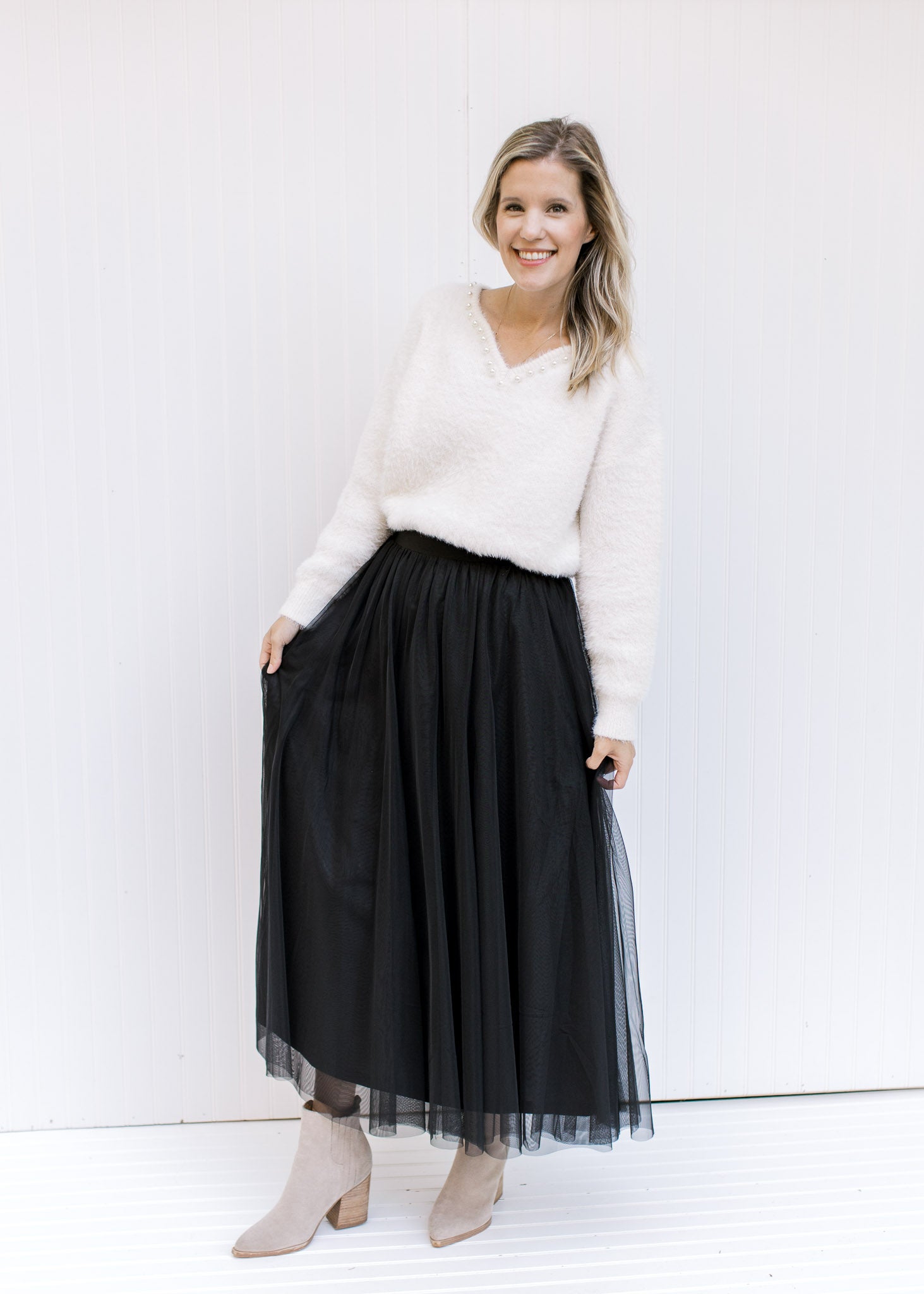 Model wearing a white top and booties with a black tulle maxi skirt with an elastic waist. 