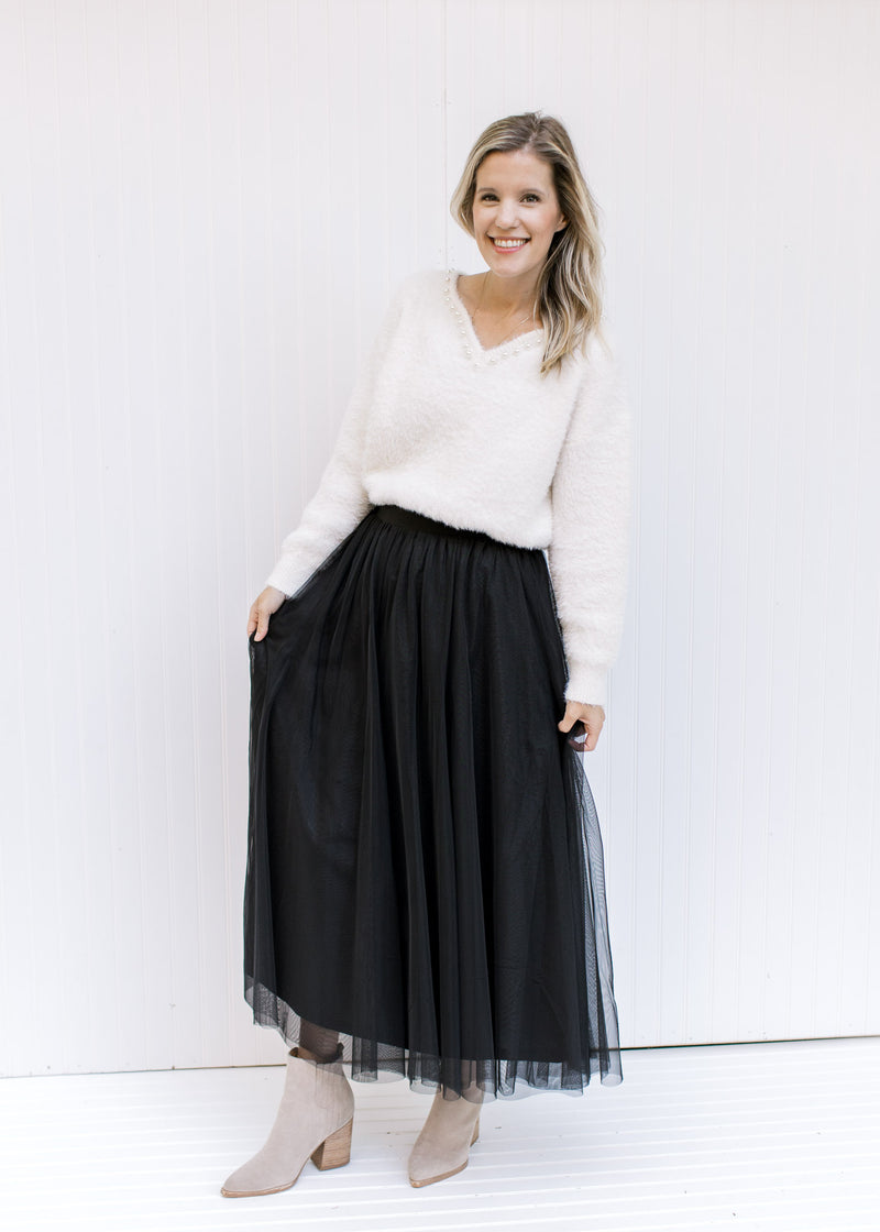 Model wearing a white top and booties with a black tulle maxi skirt with an elastic waist. 