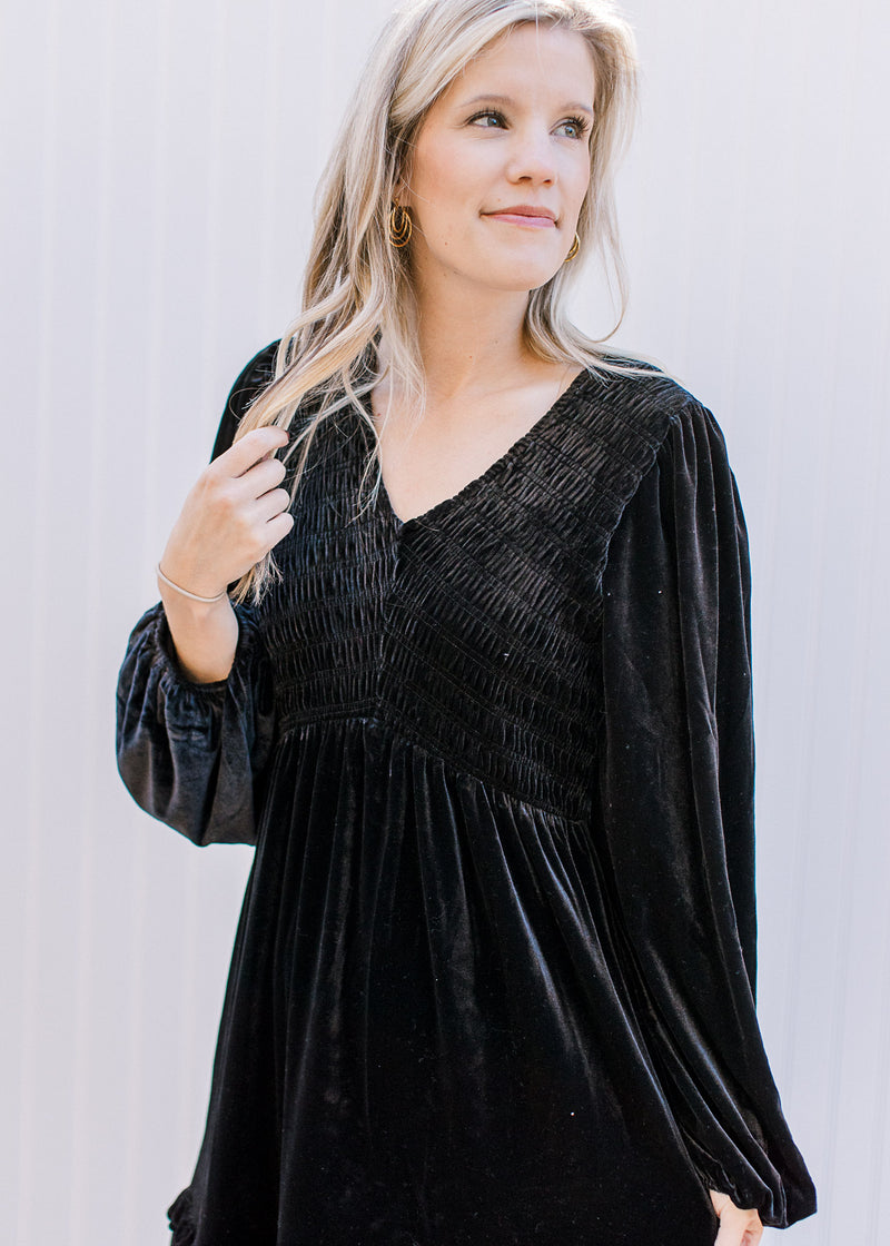 Close up of smocked bodice and v-neck on a black velvet dress with long bubble sleeves. 