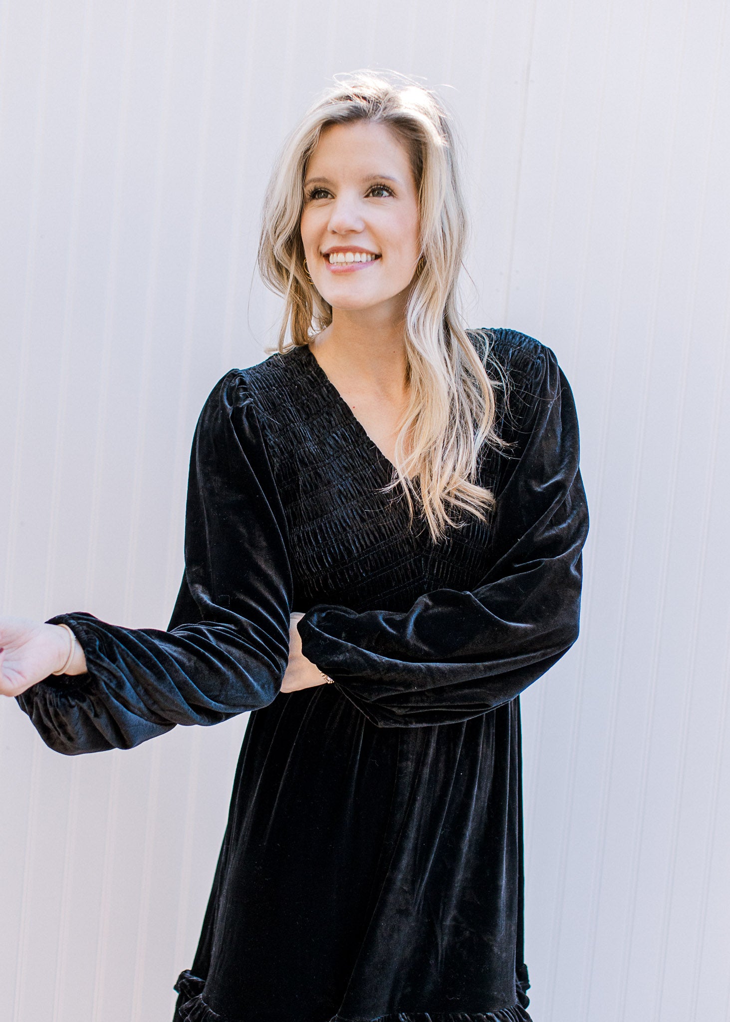 Model wearing a black velvet v-neck dress with bubble long sleeves and tiered skirt.