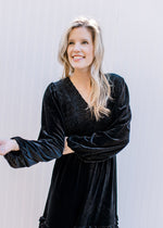 Model wearing a black velvet v-neck dress with bubble long sleeves and tiered skirt.