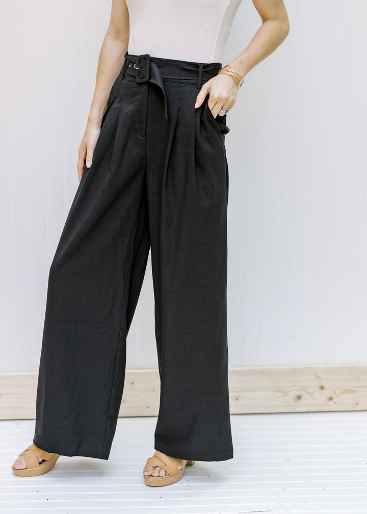 Model wearing wedges with high rise, black wide leg slacks with a belt. 