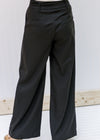 Back view of model wearing black hi rise slacks with wide legs. 