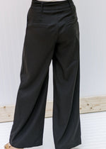 Back view of model wearing black hi rise slacks with wide legs. 