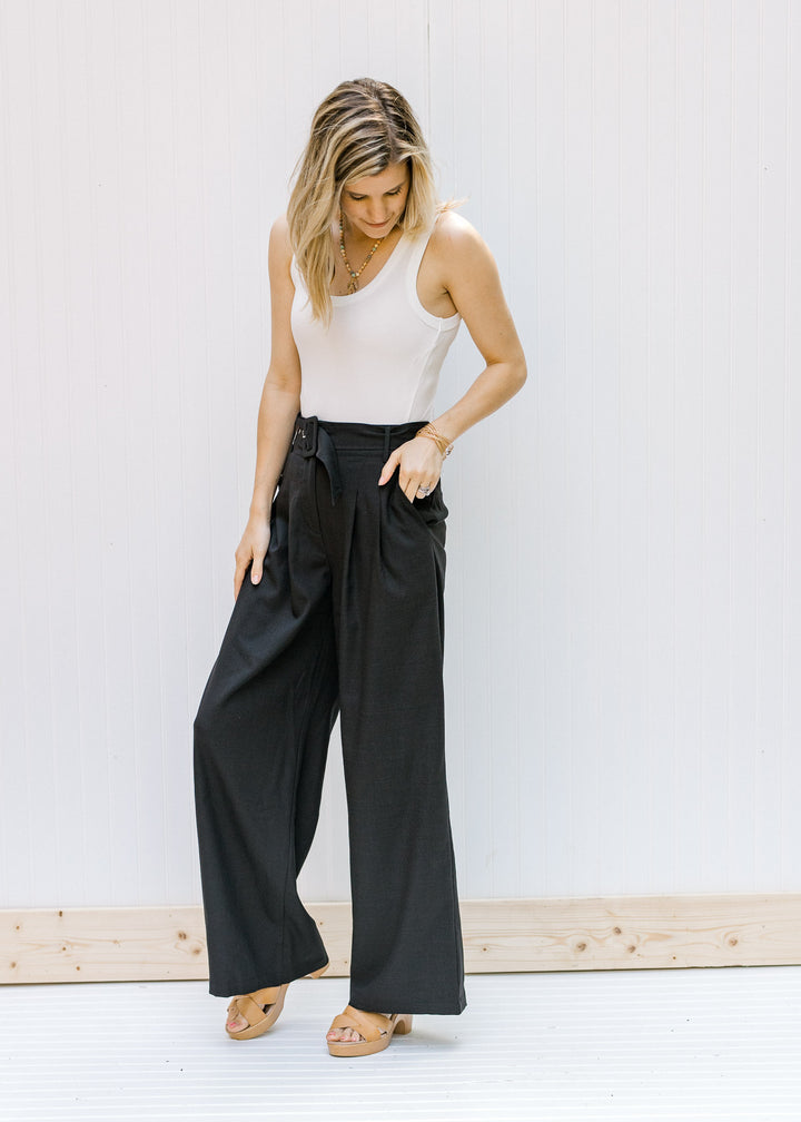 Model wearing a white tank with hi rise, black slacks with wide legs and wedges. 