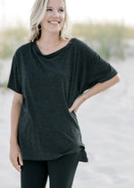 Model wearing a black, hi-low workout top with exposed seam, short sleeves and split sides. 