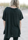 Back view of Model wearing a black workout top with exposed seam, short sleeves and split sides. 