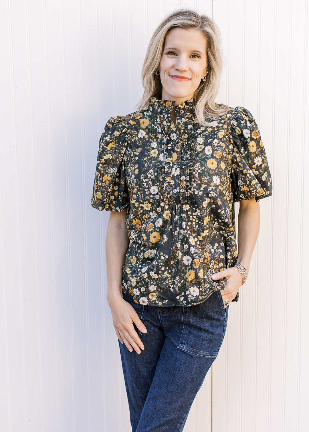 Model wearing jeans and a black top with yellow and cream floral and bubble short sleeves.