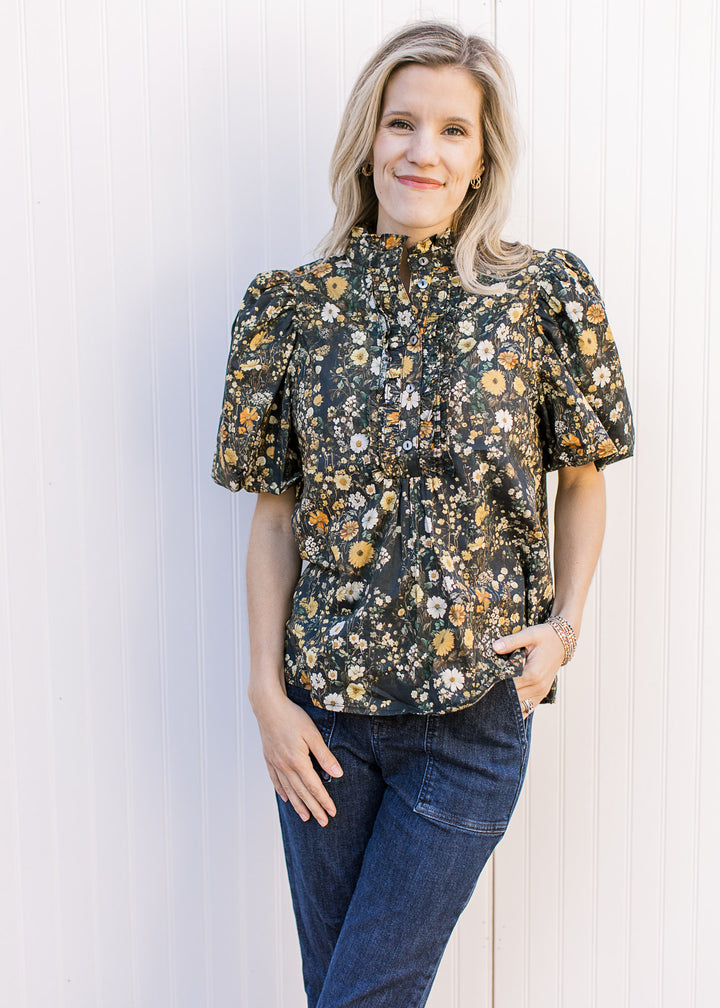 Model wearing jeans and a black top with yellow and cream floral and bubble short sleeves.
