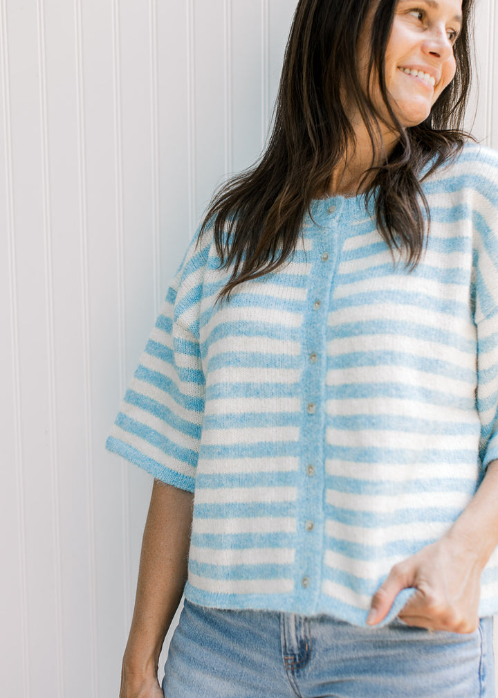 Model wearing a baby blue and cream striped cardigan with buttons and elbow-length sleeves.