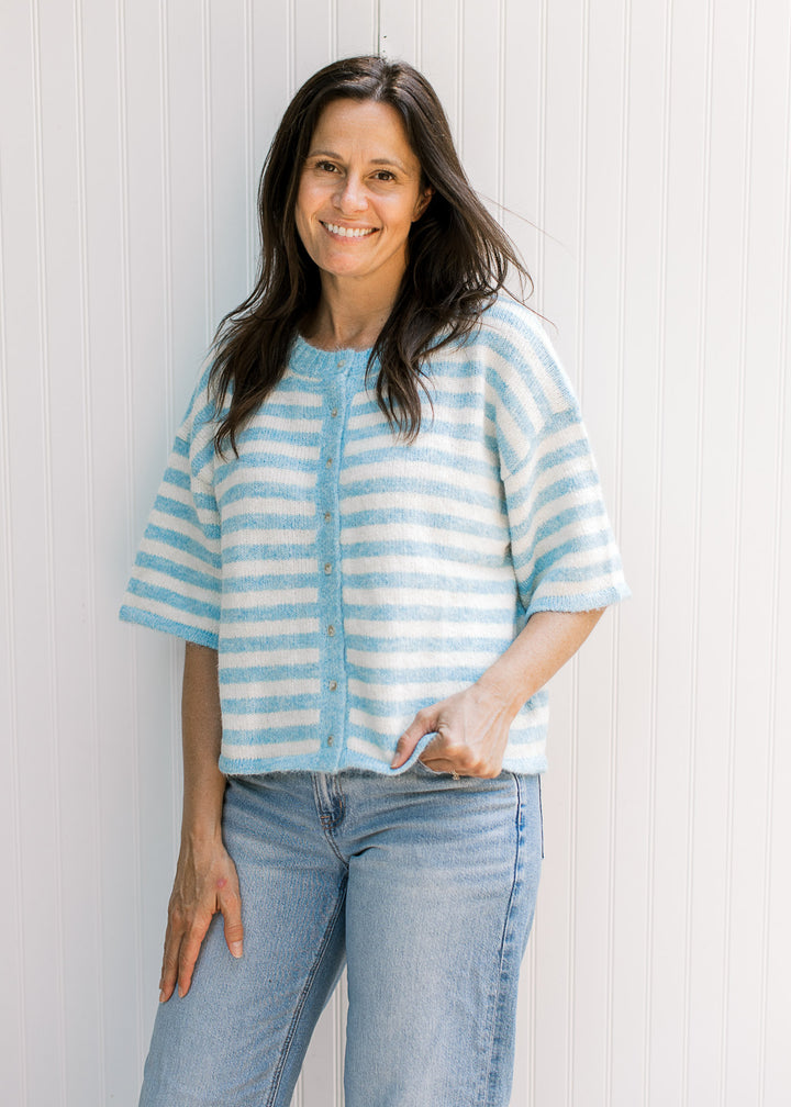 Model wearing a soft baby blue and cream striped cardigan with buttons and elbow-length sleeves.