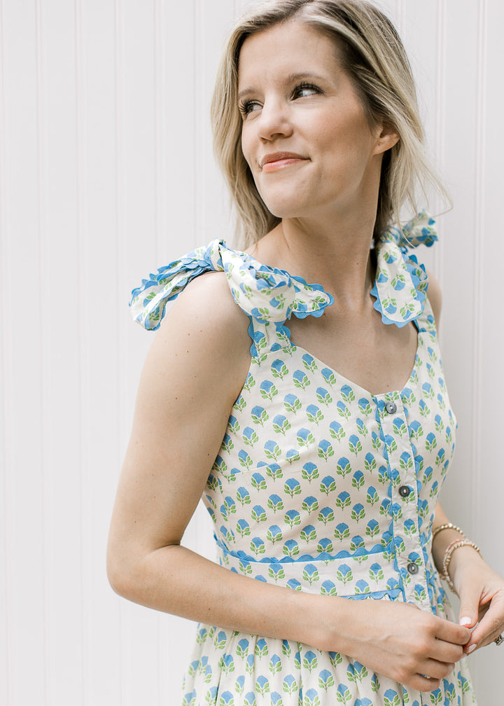 Side view of Blonde model of white dress blue and white print and shoulder tie.