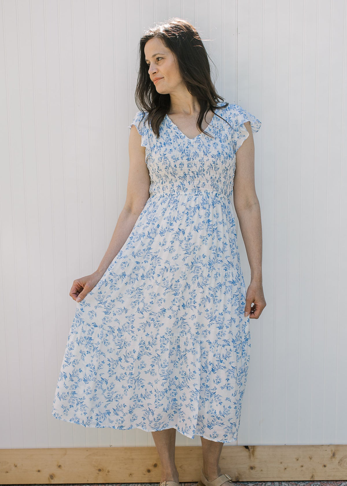 Model wearing a white with blue microfloral midi with a V-neck and ruffle capped sleeves. 