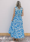 Back view of Model wearing a cream and blue floral maxi with lace inset at bodice and tie waist.